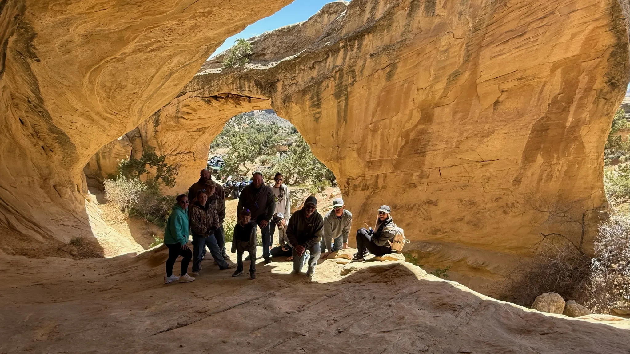 An Adventure Tours Vernal tour group posing under Moonshine Arch near Vernal, Utah
